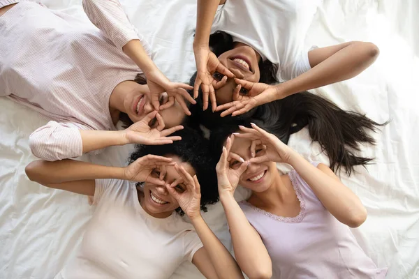Glimlachende multi-etnische dames hebben plezier op bed kijk naar camera — Stockfoto