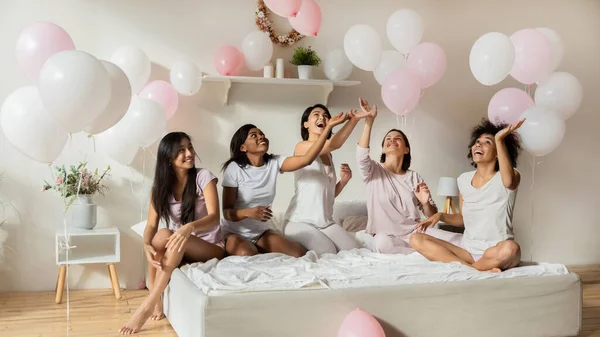 Çok ırklı güzel kadınlar yatak odasında pembe balonlarla eğleniyor. — Stok fotoğraf