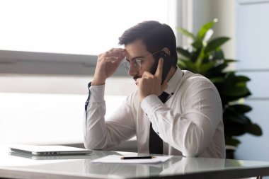 Ofiste ciddi bir Kafkas iş adamı cep telefonuyla konuşuyor.