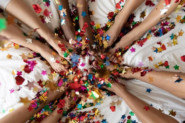 Yatakta çeşitli kadın bacakları renkli konfetilerle kaplı, yakın plan. — Stok fotoğraf