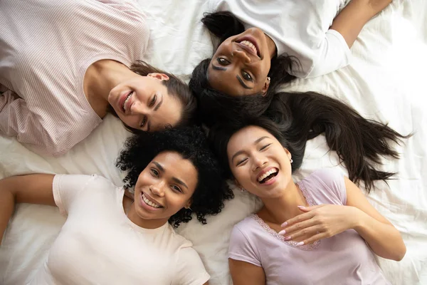 Ευτυχισμένη ποικιλόμορφη εθνικότητα νεαρά κορίτσια φίλους στο κρεβάτι, top view — Φωτογραφία Αρχείου