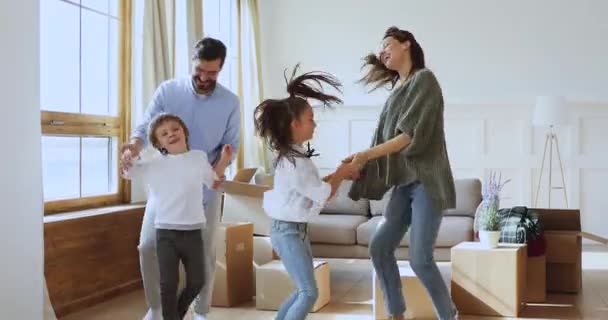 Счастливая семья из четырех танцующих прыжков, празднующих день переезда — стоковое видео