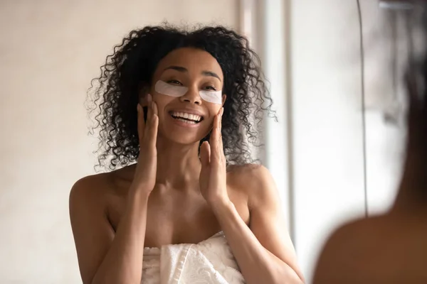 African American woman look in mirror do facial routine — Stock Photo, Image