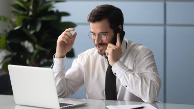 Genç işadamı ofiste dizüstü bilgisayarla konuşuyor.