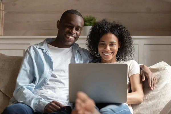 Feliz pareja afroamericana relajarse en el sofá con el ordenador portátil —  Fotos de Stock