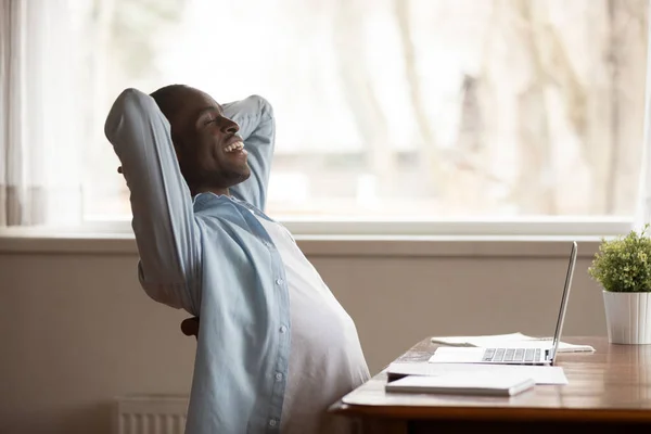 Happy african American man relaxing in chair at workplace — Stock Photo, Image