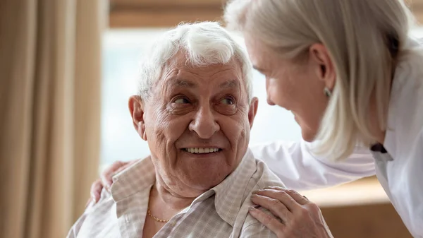 Χαρούμενος ηλικιωμένος άντρας που κοιτάζει μια ευχάριστη μεσήλικη νοσοκόμα.. — Φωτογραφία Αρχείου
