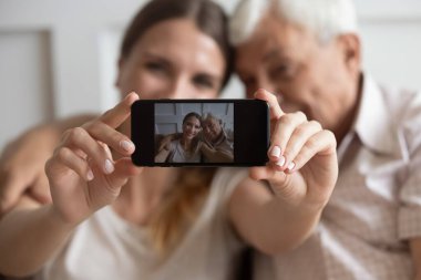 Gülümseyen kadın mutlu babasıyla cep telefonunda fotoğraf çekiyor..
