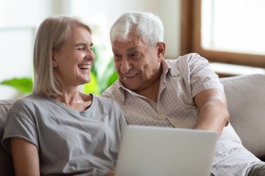 Neşeli olgun bir kadın kanepeye oturmuş neşeli yaşlı bir adamla.