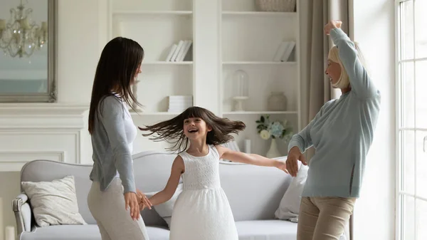 Grootmoeder volwassen dochter en kleindochter dansen in de moderne woonkamer — Stockfoto