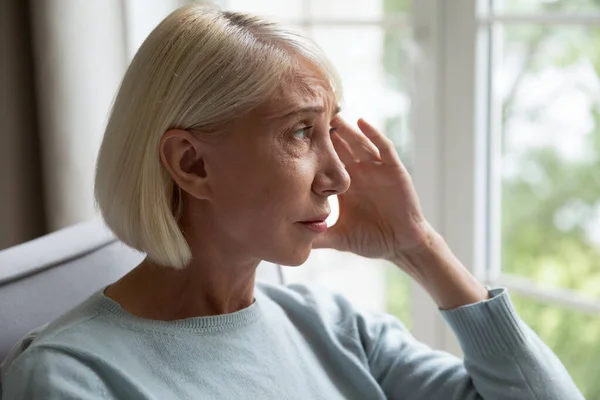 Elderly woman looking out the window feels lonely — Stock Photo, Image