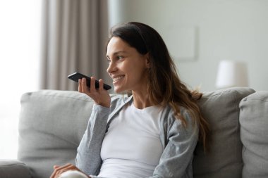 Kadın evde sesli mesaj kullanarak akıllı telefon tutarak zaman geçirmiş.