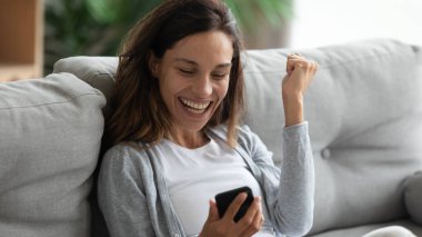 Mutlu kadın akıllı telefonu tutuyor. Uzun zamandır beklenen bir mesaj var.