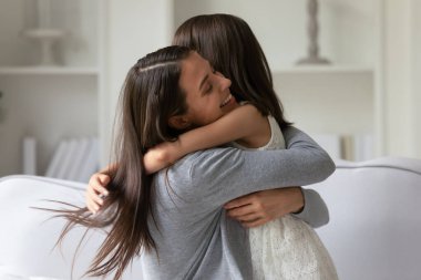 Mutlu genç anne güçlü bir şekilde küçük kızına sarılıyor.