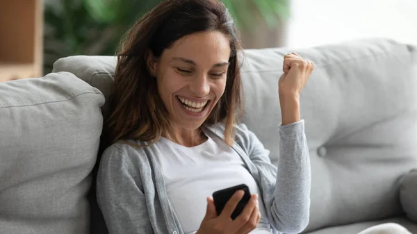 Mujer feliz sostiene teléfono inteligente tiene mensaje largamente esperado — Foto de Stock