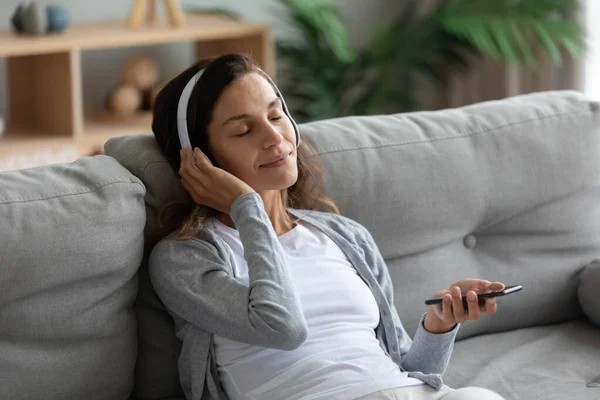 A fejhallgatót viselő nő élvezi a zenét okostelefonon — Stock Fotó