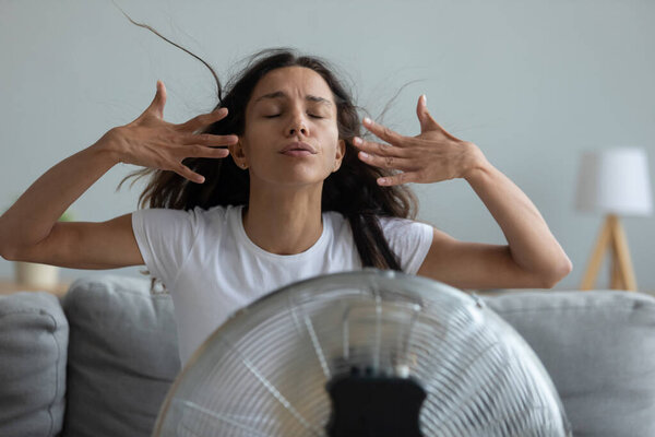 Woman waving hands trying to cool off herself by fan