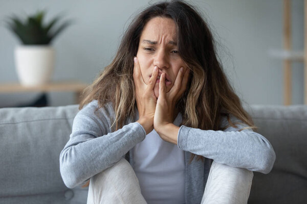 Closeup of female sitting on couch looking unhappy and desperate