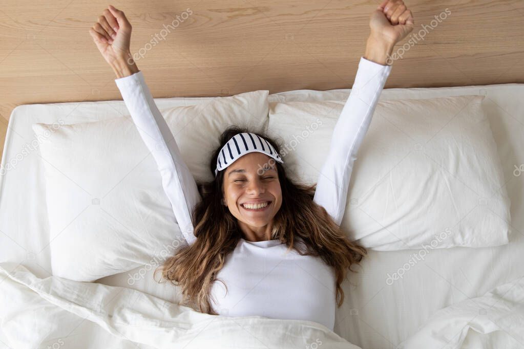 Happy awakened woman took off mask stretching after night sleeping