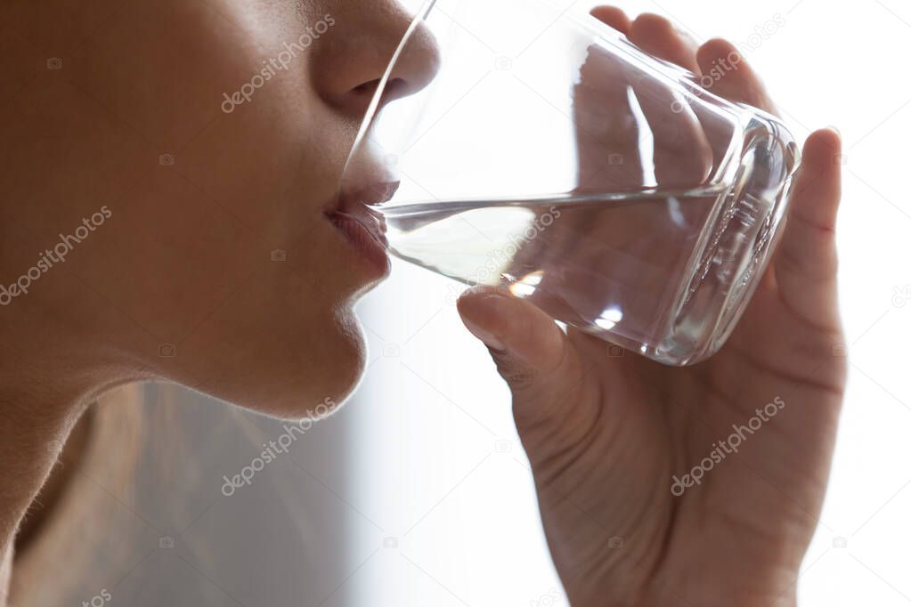 Closeup women face and hand holding glass of water