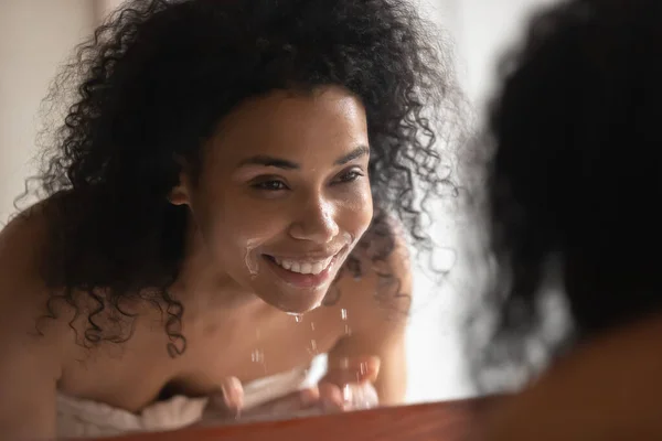 Lächelnde Afroamerikanerin wäscht Gesicht in klarem Wasser — Stockfoto