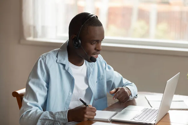 Skoncentrowany człowiek birasowy w słuchawkach badania na laptopie — Zdjęcie stockowe