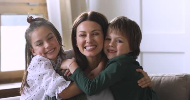 Loving mommy and cute children embracing laughing looking at camera — Stock Video