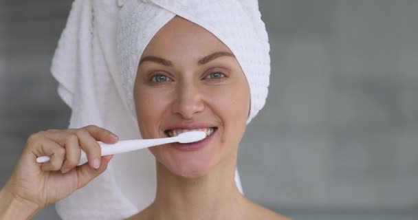 Beautiful young woman brushing teeth looking at camera — Stock Video