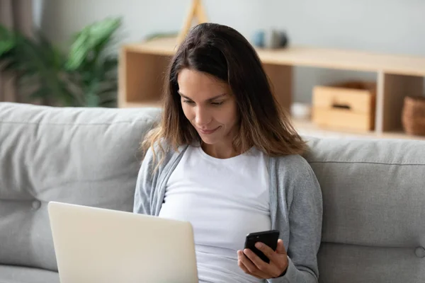 Laptop ve akıllı telefon kullanan bir kadın bluetooth kullanarak iki aygıt eşleştiriyor — Stok fotoğraf