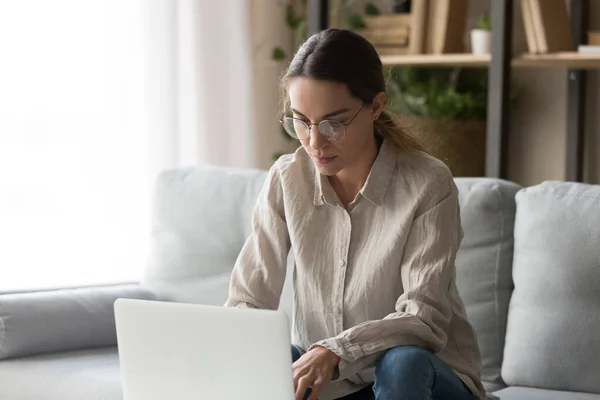 Focused young woman busy working at laptop from home — Stock Photo, Image