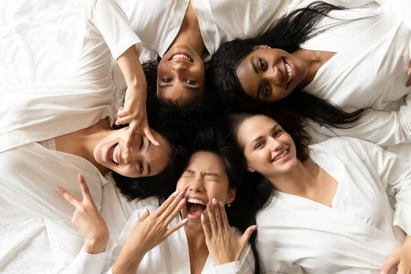 Vijf gelukkig divers jong meisjes liggend op bed, top uitzicht — Stockfoto