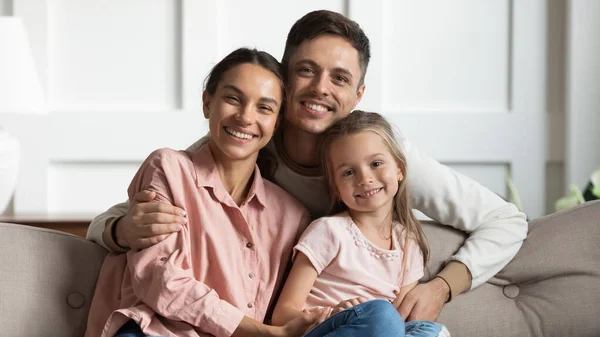 Mooie jonge ouders met kleine dochter zitten op de bank, portret — Stockfoto