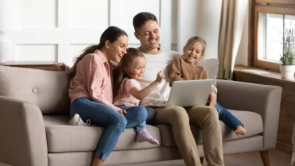 Веселые родители и дети, пользующиеся ноутбуком, веселятся дома — стоковое фото