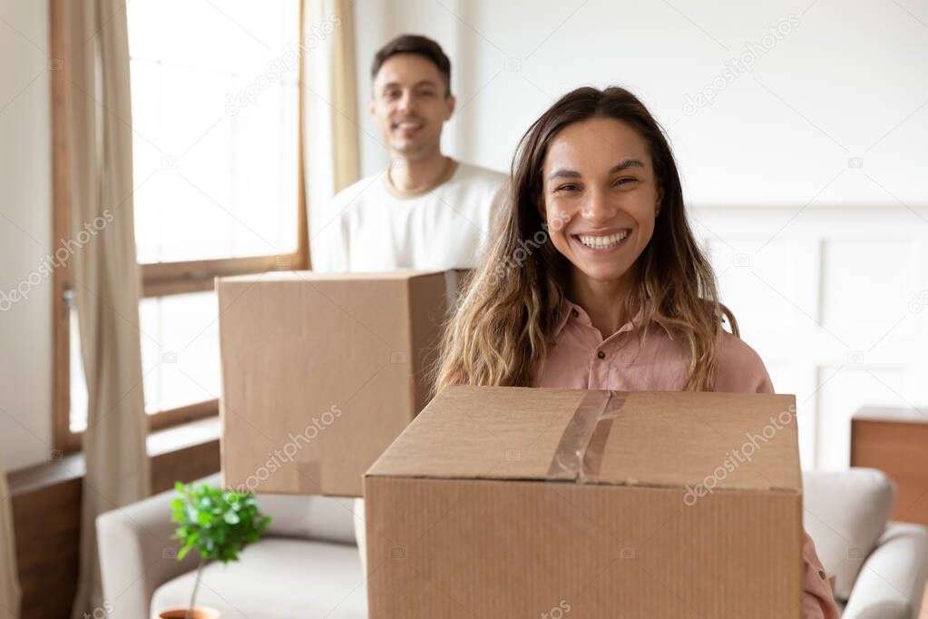 Smiling wife holding box relocating into new home with husband