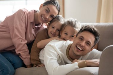 Dört kişilik mutlu bir aile kanepeye oturmuş kameraya bakıyor.