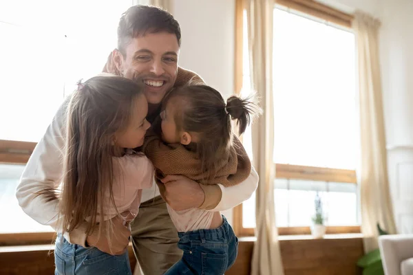 Loving young father hugging sweet small kids daughters at home — Stock Photo, Image