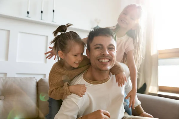 Gelukkig vader spelen met leuke kleine dochters kijken naar camera — Stockfoto