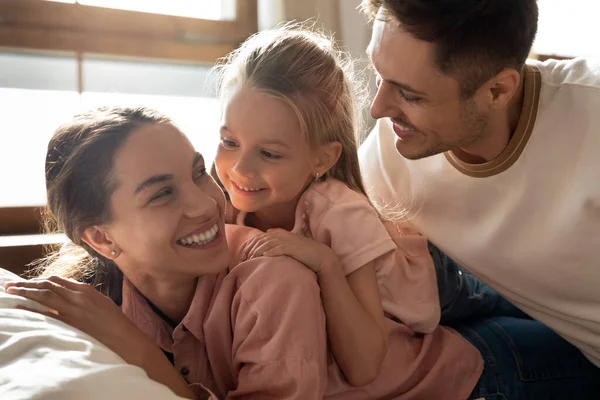 Gelukkig ouders en schattig meisje dochter bonding liggend op bed — Stockfoto