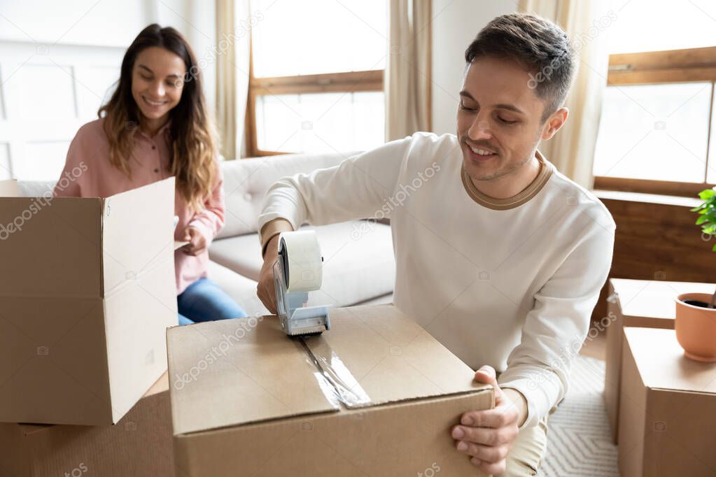 Happy young family couple renters packing on moving day together