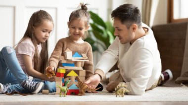 Küçük baba ve küçük kızları evde birlikte oynuyorlar.
