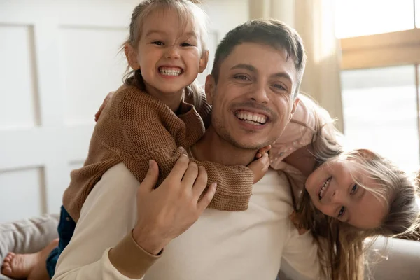 Смешной отец и двое детей дочери обнимаются, глядя в камеру. — стоковое фото