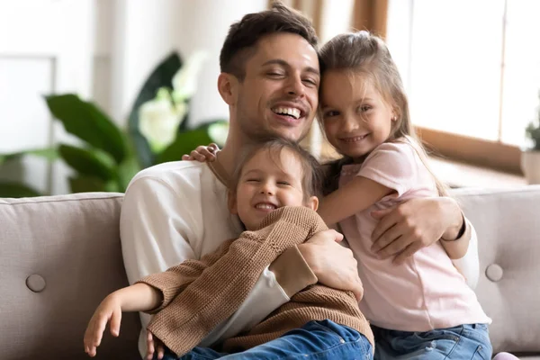 Zorgzame papa en schattig kinderen meisjes bonding knuffelen op bank — Stockfoto