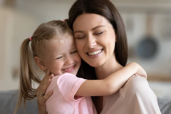 Турбота про усміхнену прийомну матір обіймає милу усиновлену доньку вдома — стокове фото