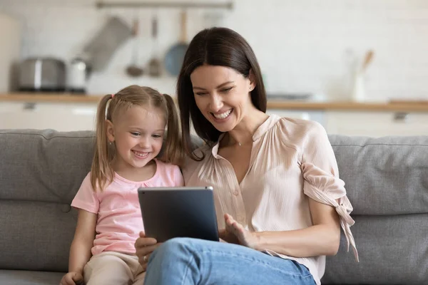 Mãe alegre com filha criança usando tablet digital em casa — Fotografia de Stock