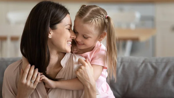 Söt liten dotter kram vårda ung mamma krama på soffan — Stockfoto