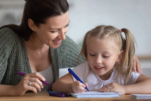 La mamma premurosa aiuta la bambina a disegnare un quadro con pennarelli — Foto Stock