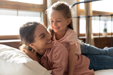 Mutlu bir anne ve kız çocuğu yatakta gülüyor.