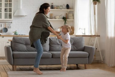 Heyecanlı anne ve kızı modern mutfakta birlikte dans ediyor.