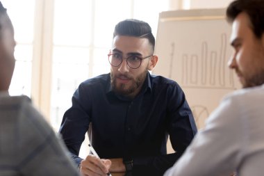 Orta Doğu etnik kökenli genç işadamı çok ırklı ortakları dinliyor..