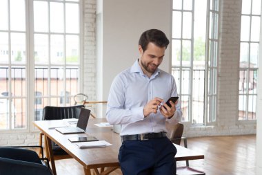 Gülümseyen kendine güvenen ofis müdürü cep telefonu kullanıyor, tatilin tadını çıkarıyor..